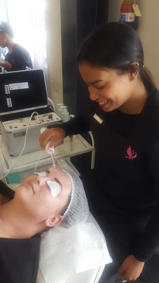Esthetician performing a facial electrical treatment on a client