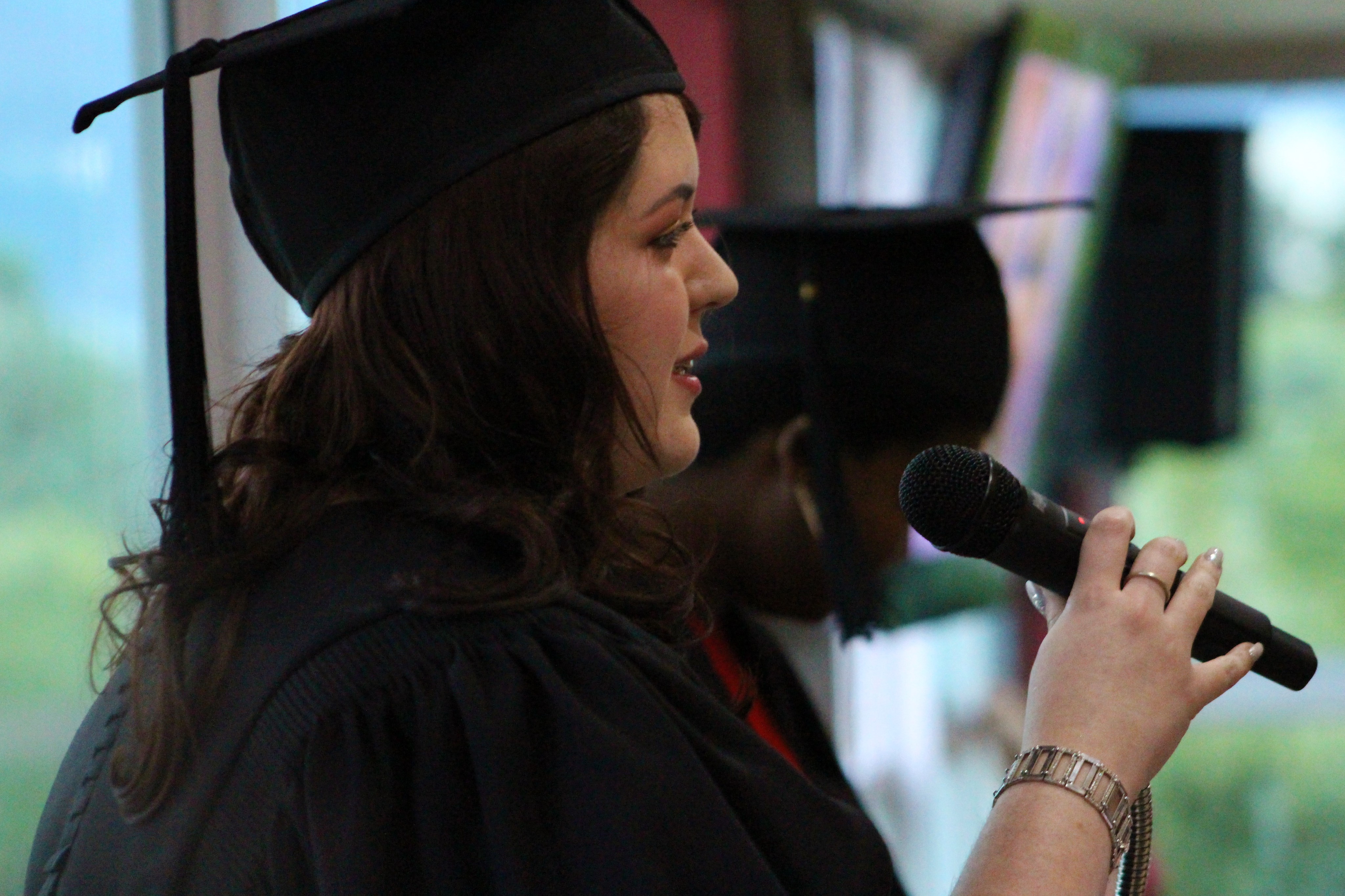 Graduate speaking into a microphone at a ceremony