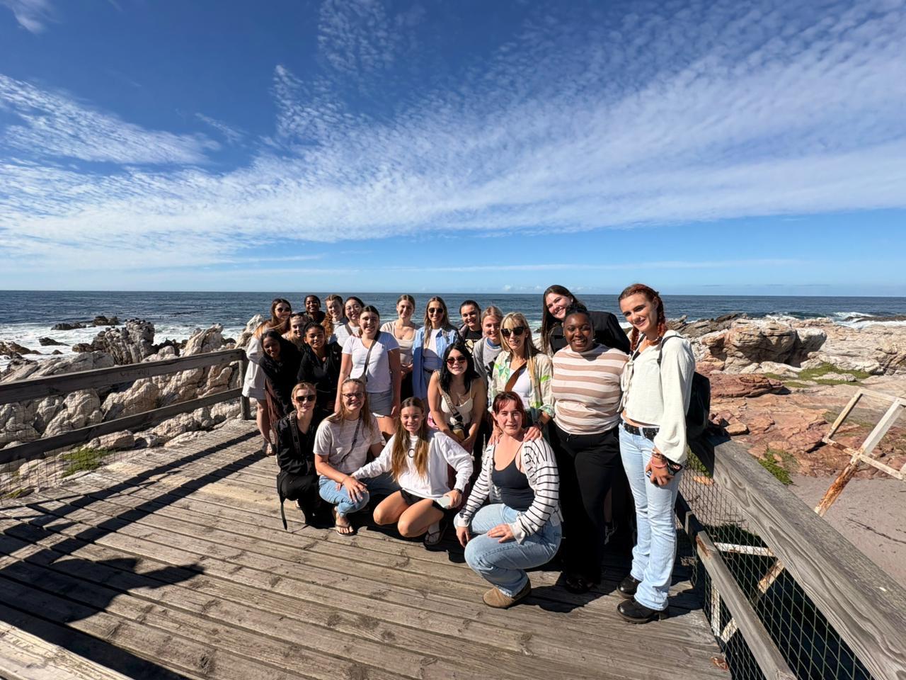 Students group photo on a coastal boardwalk with ocean views