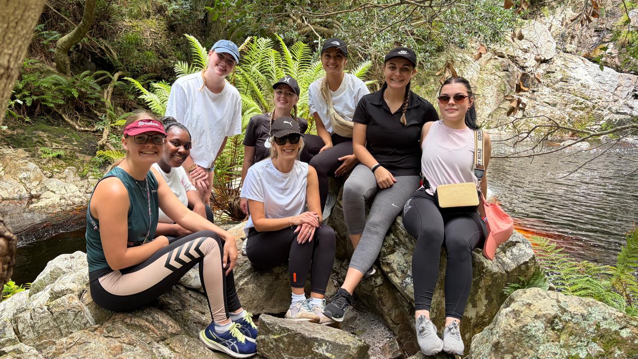 Students posing together on rocks by a stream during a nature hike