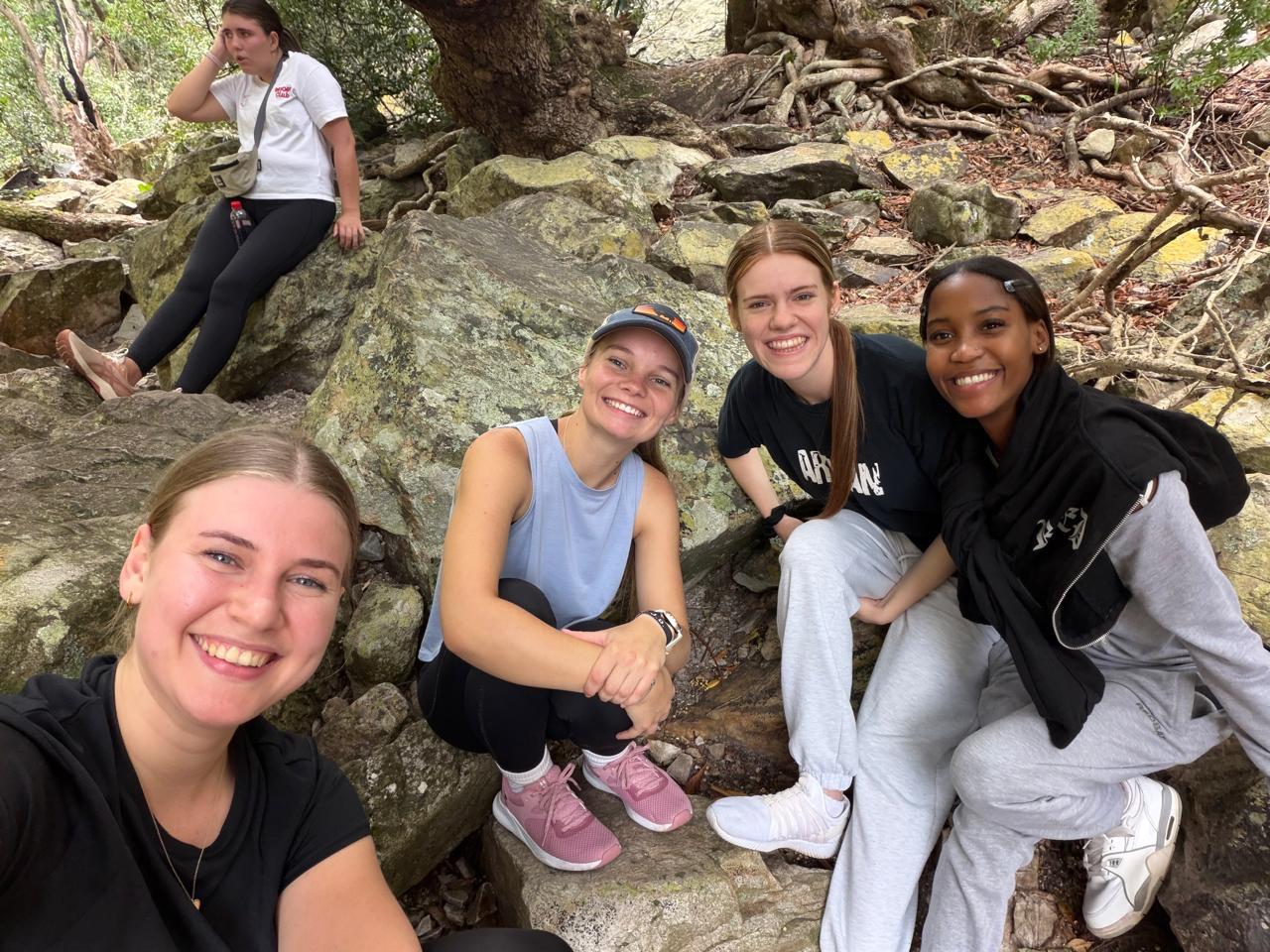 Students taking a selfie on rocks during a hiking adventure