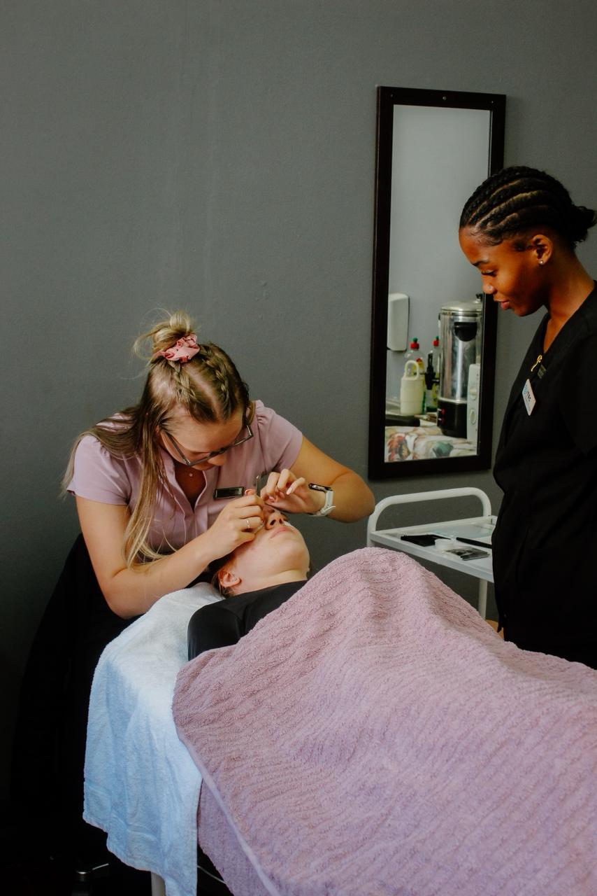 Student performing an eyebrow treatment supervised by an instructor