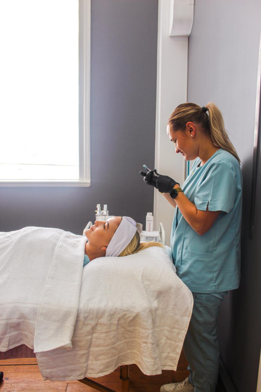 Student preparing a facial device treatment on a client