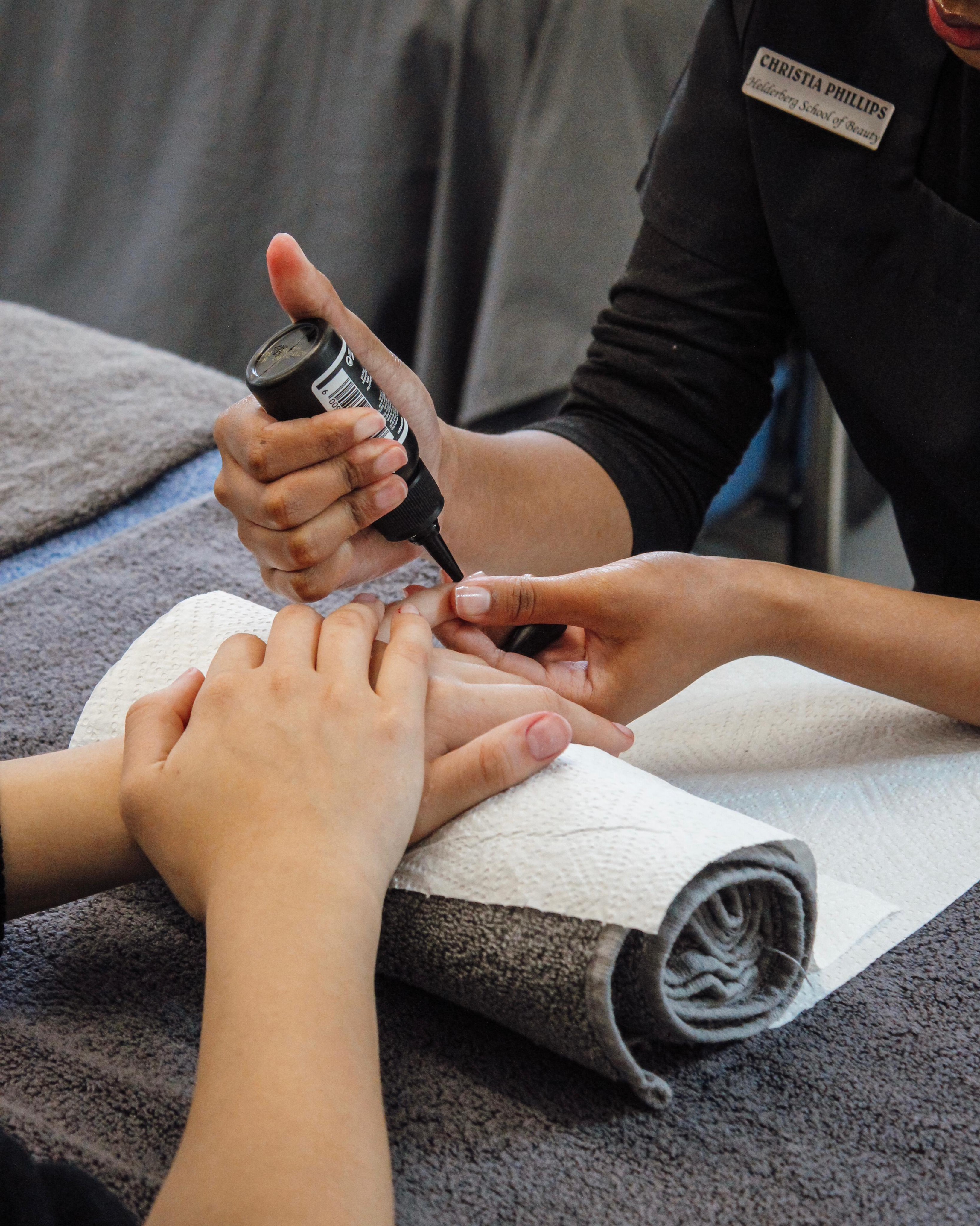 Student applying nail polish during a manicure training session