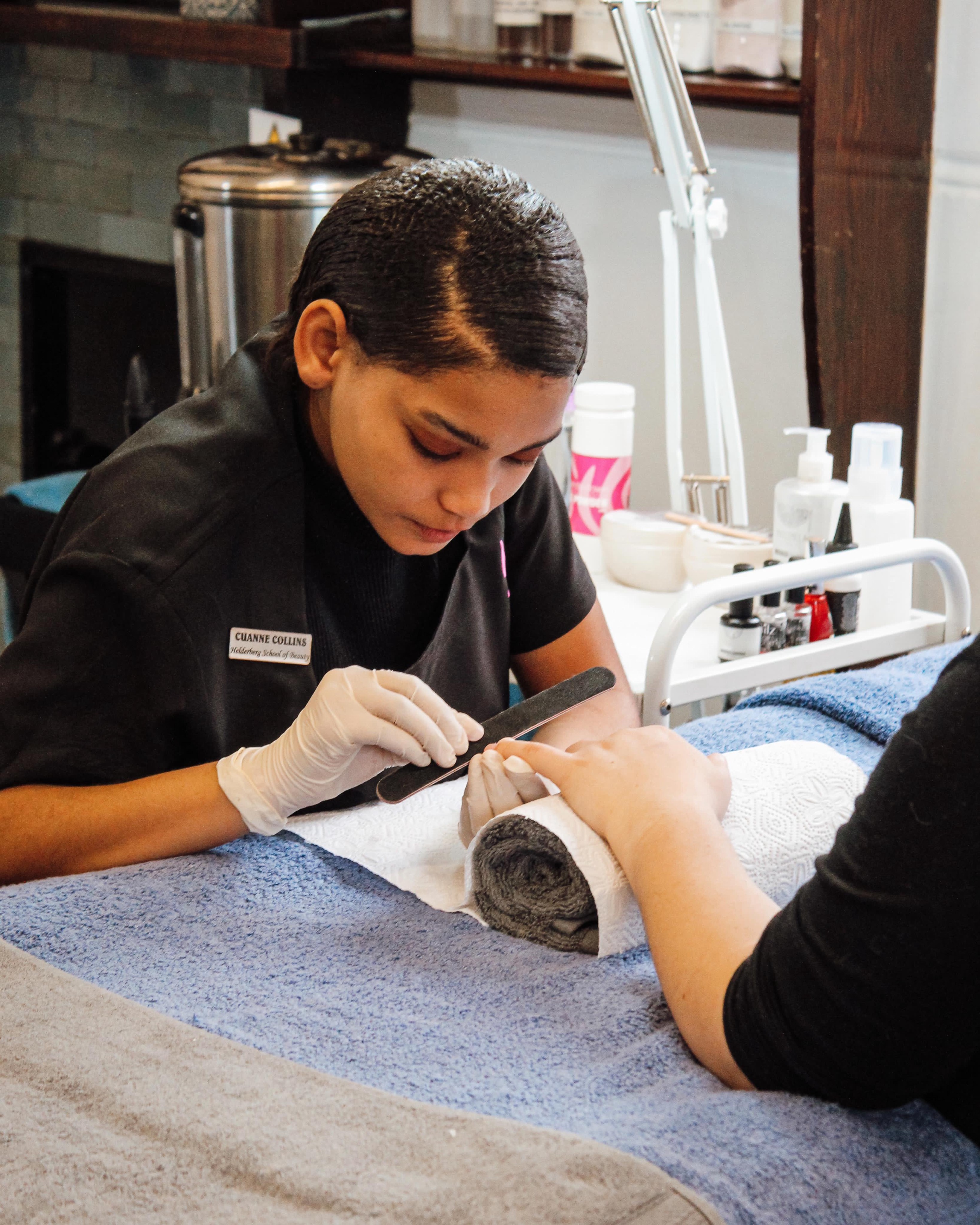 Student filing nails during a manicure practical at Helderberg School of Beauty